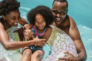 Family Enjoying Summer Holidays In Pool