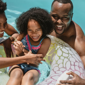 Family Enjoying Summer Holidays In Pool